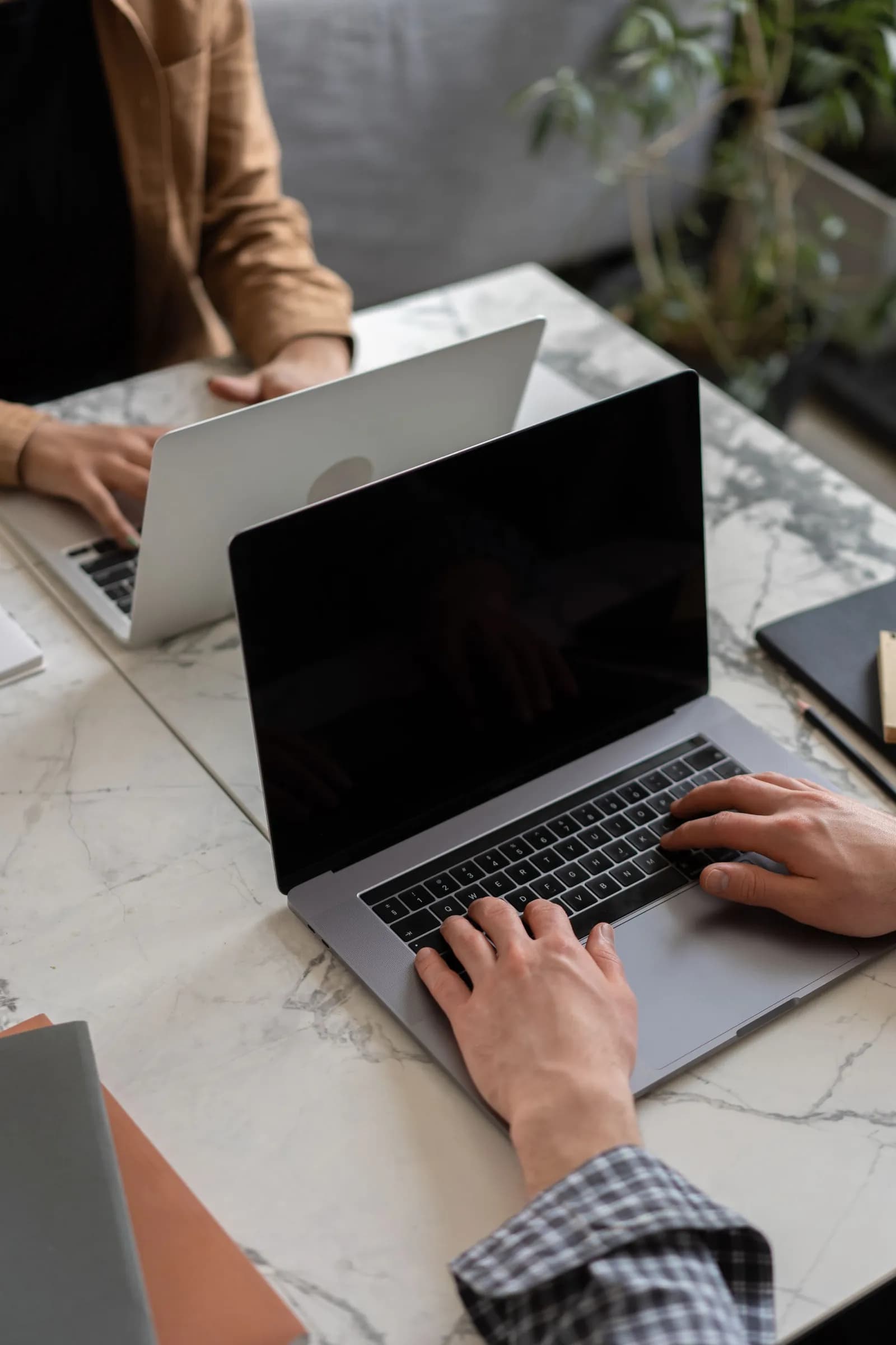 Two people working on laptops at a shared desk